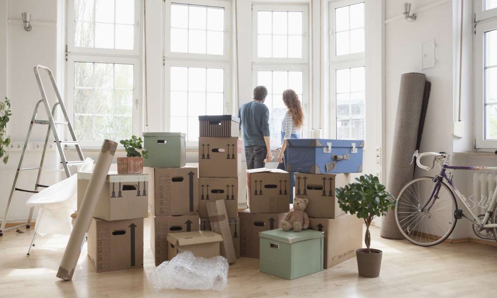 couple-with-cardboard-boxes-in-new-apartment-looking-out-of-window-668769389-5b6d106d46e0fb002c78c375